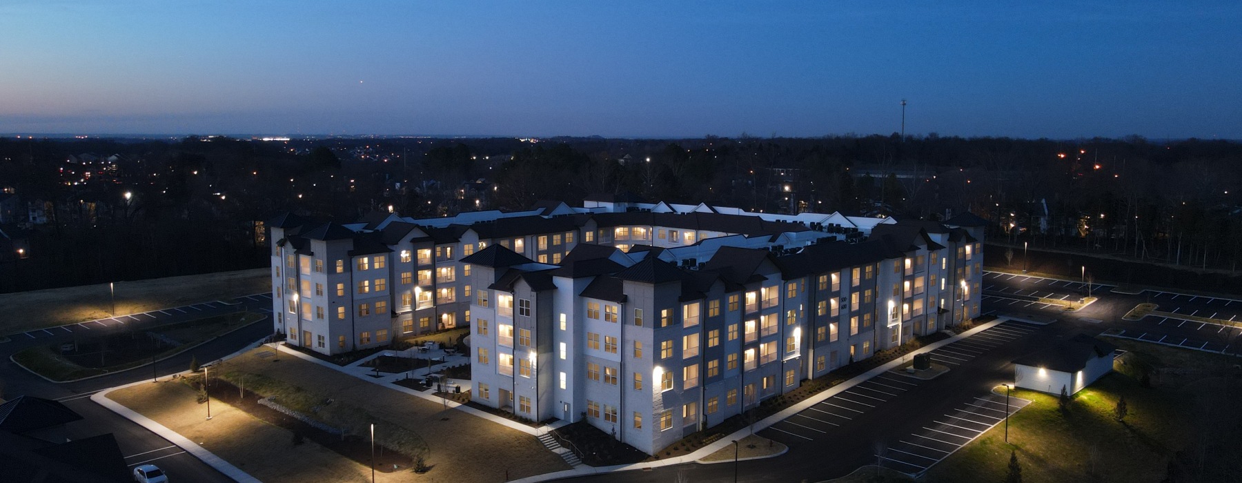 Aerial view of four-story apartment building at night with all lights turned on