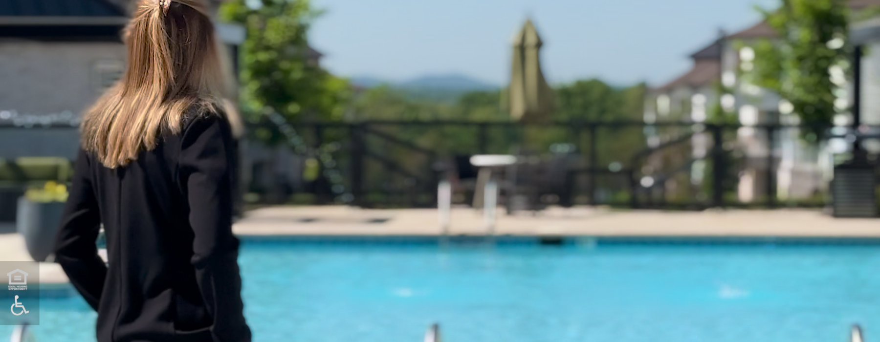 Resident looks out over the salt-water pool, the grand courtyard, and the distant Tennessee hills at the Ravelle apartment community in Antioch, TN.